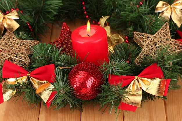 Composição de Natal com velas e enfeites nas cores vermelho e dourado na mesa de madeira.