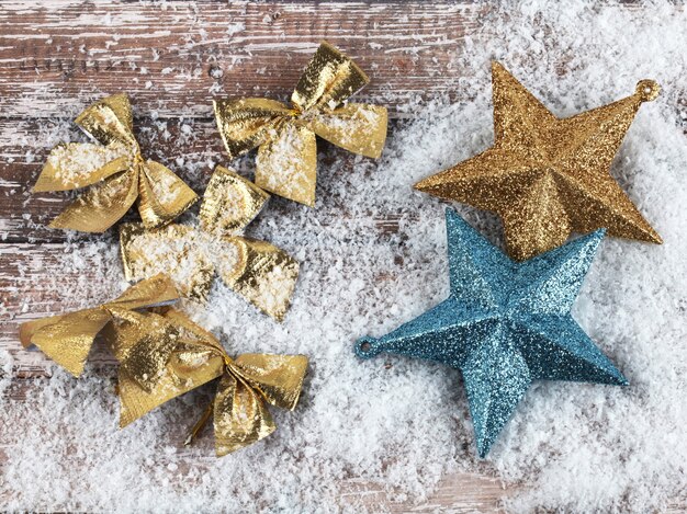 Composição de Natal de arcos de ouro e estrelas na superfície de madeira coberta de neve. Vista do topo