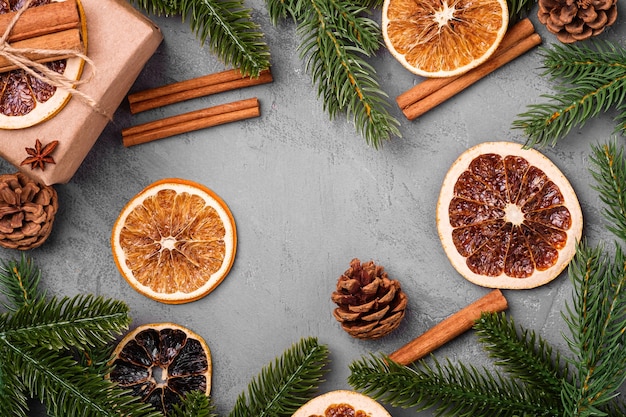 Composição de Natal. Decoração de caixa de presente, canela, anis, frutas secas, pinhas e agulhas de abeto em fundo cinza. Espaço de cópia da vista superior