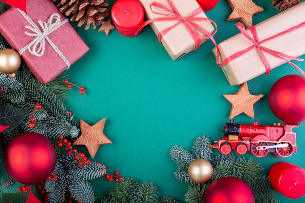 Composição de Natal. Decorações de Natal verde, galhos de árvore do abeto com caixas de presente de brinquedos sobre fundo verde. Camada plana, vista superior, espaço de cópia.