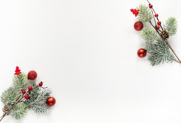 Composição de Natal. Galhos de árvore do abeto com decorações vermelhas sobre fundo branco. Conceito de ano novo. Camada plana, vista de cima, espaço de cópia