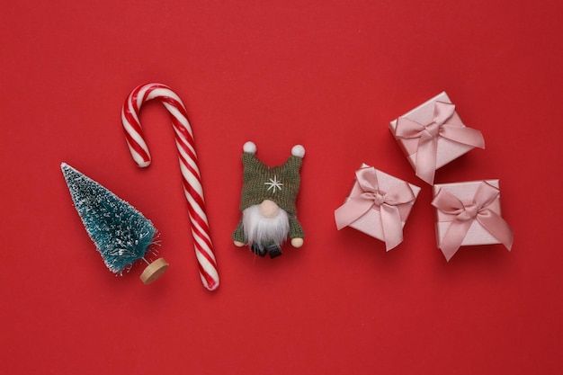 Composição de Natal Gnomo de árvore de Natal e caixas de presente de cana-de-doce em fundo vermelho