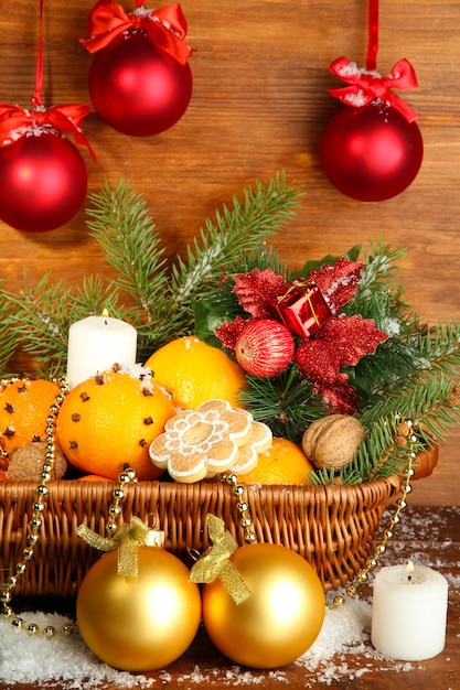 Composição de Natal numa cesta com laranjas e pinheiros, em fundo de madeira.