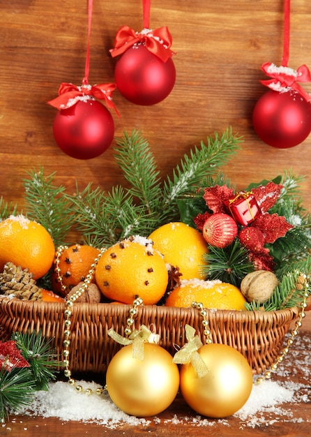 Composição de Natal numa cesta com laranjas e pinheiros, em fundo de madeira.