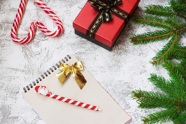 Composição de Natal ou Ano Novo de ramos verdes de abeto, presente, caderno e pirulitos de Natal