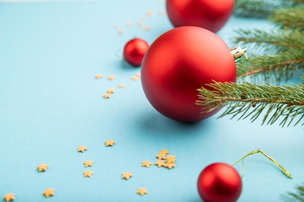 Composição de Natal ou Ano Novo. Decorações, bolas vermelhas, ramos de abeto e abeto, sobre um fundo de papel azul. Vista lateral, copie o espaço.
