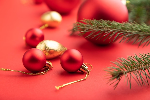 Composição de Natal ou Ano Novo. Decorações, bolas vermelhas, ramos de abeto e abeto, sobre um fundo de papel vermelho. Vista lateral, foco seletivo, close-up.