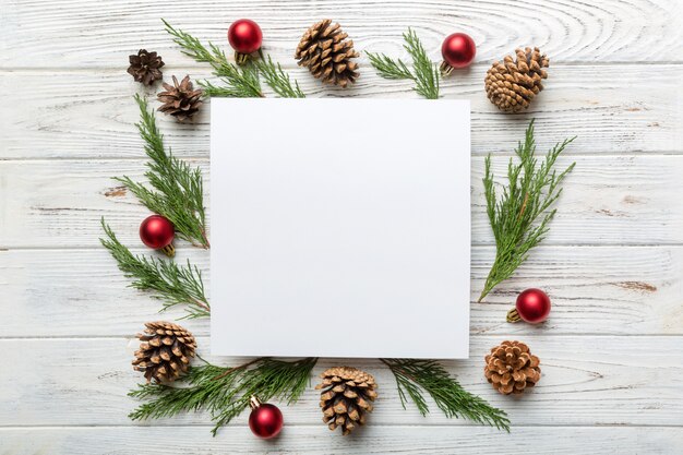 Composição de natal plana leigos. quadrado em branco de papel, galhos de pinheiro, decorações de natal em fundo colorido. vista superior, copie o espaço para o texto