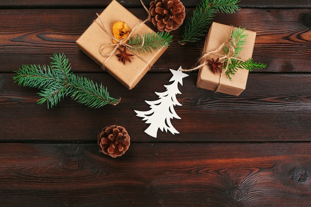 Composição de Natal. Presente de Natal, cobertor de malha, pinhas, ramos de abeto na mesa de madeira.