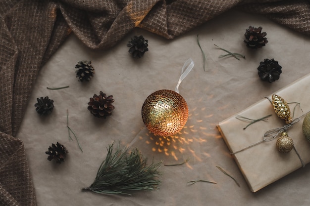 Composição de Natal. Presente, galhos de árvore do abeto, bolas no fundo do papel ofício. Natal, inverno, conceito de ano novo. Camada plana, vista superior, espaço de cópia.