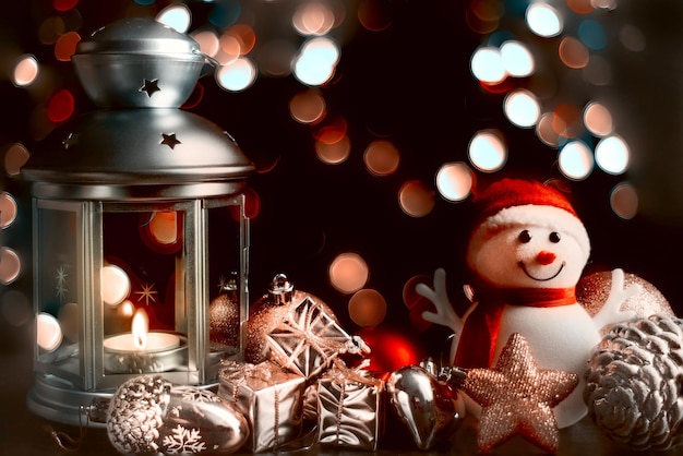 Composição de natal um boneco de neve uma lanterna com velas caixas brilhantes brilhantes com presentes bokeh desfocado