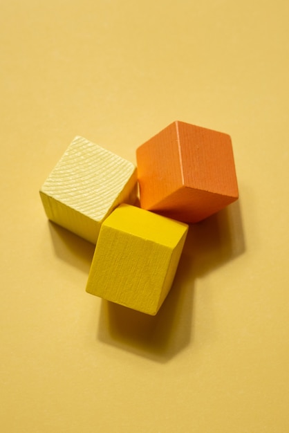 Composição de natureza morta de figuras geométricas laranja amarelo. Objetos de cubo de jogo de madeira na superfície amarela. conceito de simplicidade vista superior com sombra vertical