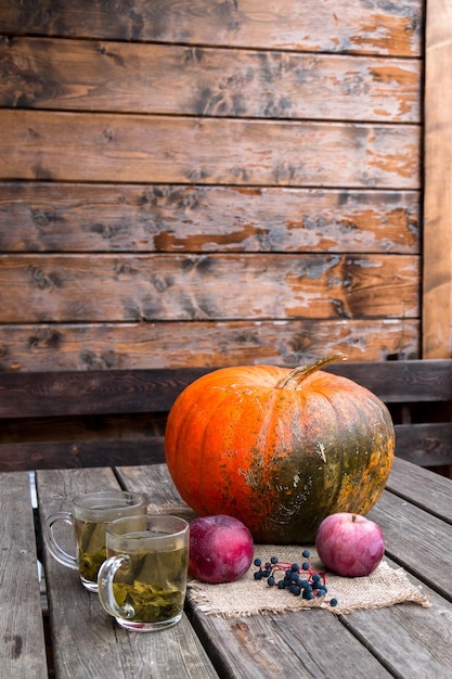 composição de outono, abóbora, maçãs, uvas em uma mesa de madeira no terraço