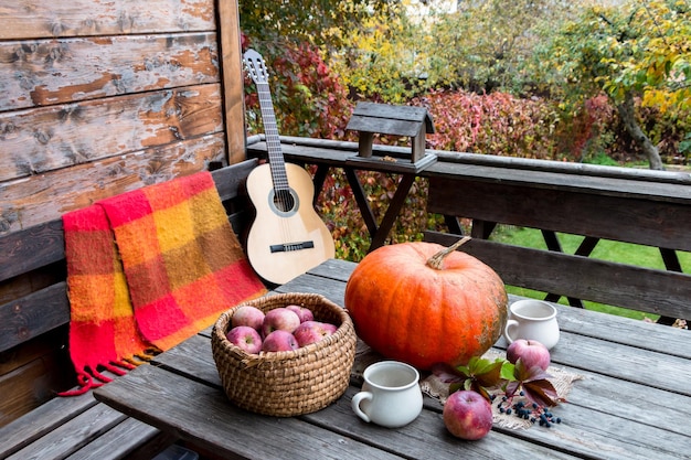 composição de outono com abóbora e maçãs e uma guitarra em um lugar aconchegante de terraço aberto