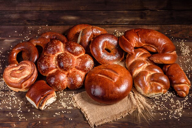 Composição de pães doces cozidos frescos com papoula e geléia. Cozimento doce, disposto como uma composição em uma mesa de madeira