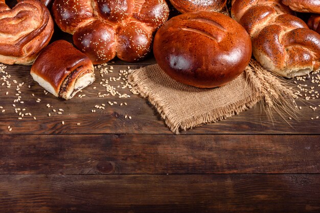 Composição de pães doces cozidos frescos com papoula e geléia. Cozimento doce, disposto como uma composição em uma mesa de madeira