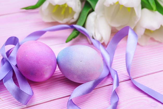 Composição de Páscoa com ovos coloridos e tulipas com fita violeta