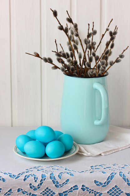 Composição de Páscoa com salgueiros em uma jarra esmaltada e ovos azuis em um prato