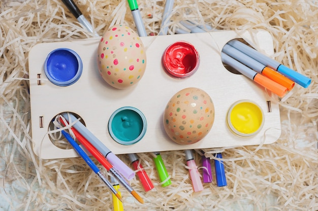 Foto composição de páscoa de ovos em uma superfície de feno. criatividade infantil. pintando ovos.