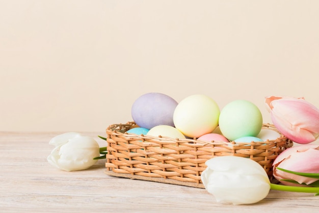Composição de Páscoa Feliz Ovos de Páscua em cesta em mesa colorida com tulipas amarelas Ovos coloridos naturais de fundo com espaço de cópia