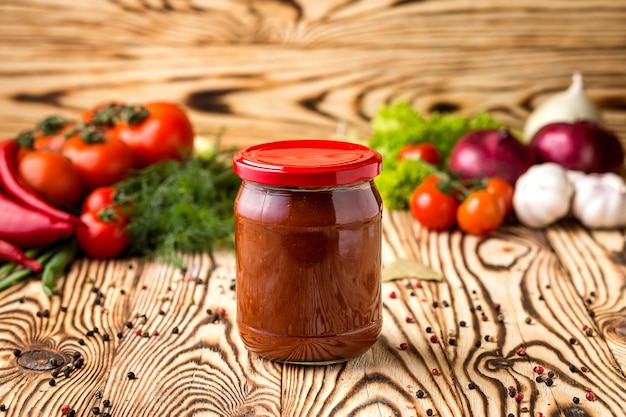 Composição de pasta de tomate ketchup em frasco e ingredientes em fundo de madeira