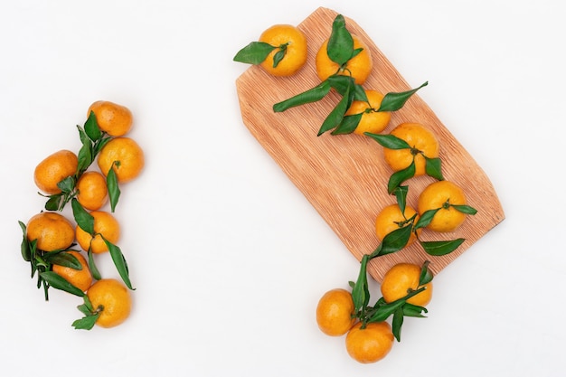 Composição de pequenas tangerinas com folhas verdes em branco