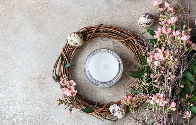 Composição de primavera com coroa trançada de galhos com flores, ovos de codorna e vela