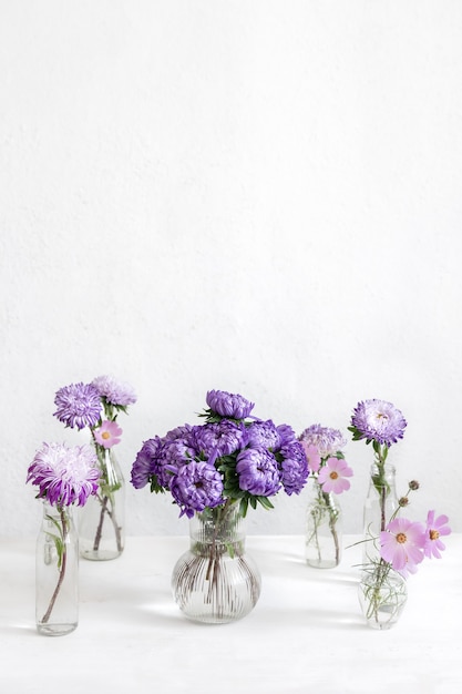 Composição de primavera com flores de crisântemo em vasos de vidro em um fundo branco turva, copie o espaço.