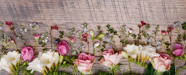 Composição de primavera ou verão feita de belas flores, ervas e bagas em floristi de pano de fundo de madeira
