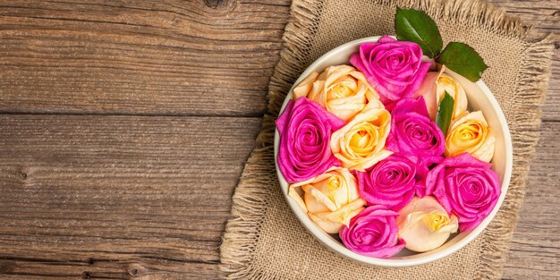 Composição de rosas frescas multicoloridas em tigela de cerâmica. O conceito festivo para casamentos, aniversários, dia 8 de março, dia das mães ou dos namorados. Cartão de felicitações, postura plana, mesa de madeira vintage