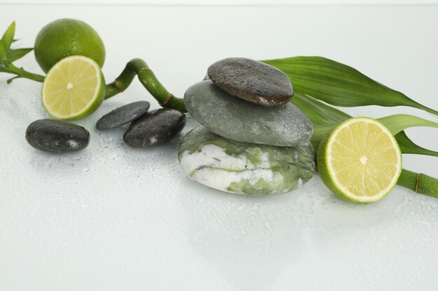 Composição de spa com pedras de massagem de limão e caule de bambu em superfície úmida