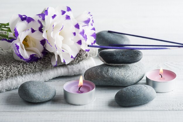 Composição de spa com toalhas, velas acesas, palitos de aroma roxo