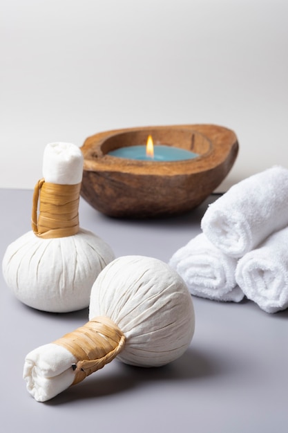 Composição de spa de uma massagem com bola de ervas, toalha com uma vela.