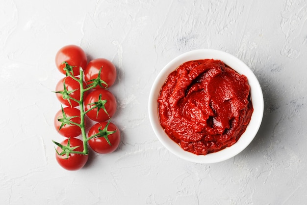 Foto composição de um ramo de molho de tomate de tomate cereja fresco em uma molheira em um fundo de mármore