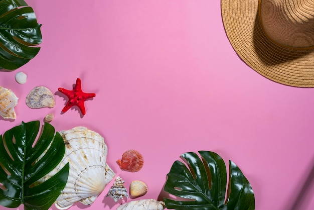 Composição de verão. Folhas de palmeira tropical, chapéu, conchas no fundo violeta pastel