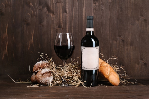 Foto composição de vinho tinto com garrafa de pão e copo de vinho na mesa de madeira