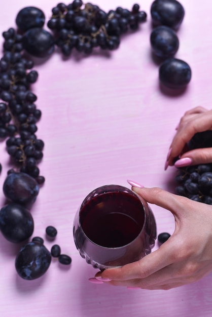Composição de vinho, uva e ameixa em um fundo rosa
