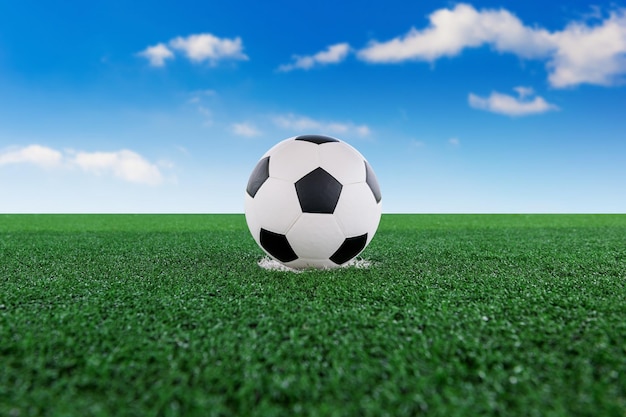 Composição digital de bola de futebol no campo de jogo contra o céu