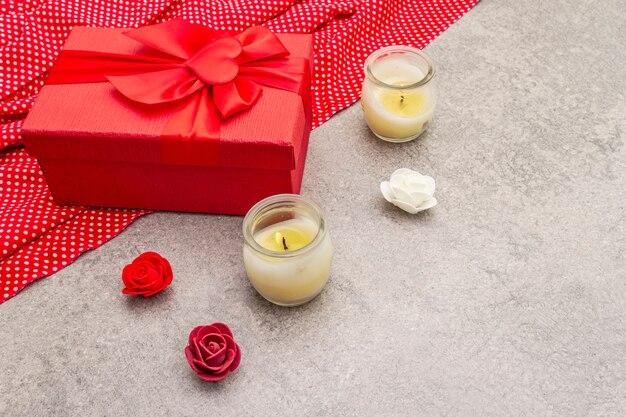 Composição do dia dos namorados com caixa de presente vermelha, pano pontilhado, velas e rosas