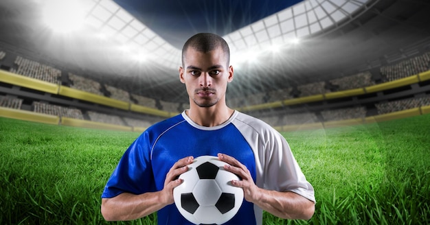 Composição do jogador de futebol masculino segurando uma bola de futebol sobre o estádio esportivo