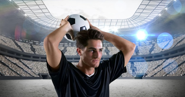 Composição do jogador de futebol masculino segurando uma bola de futebol sobre o estádio esportivo