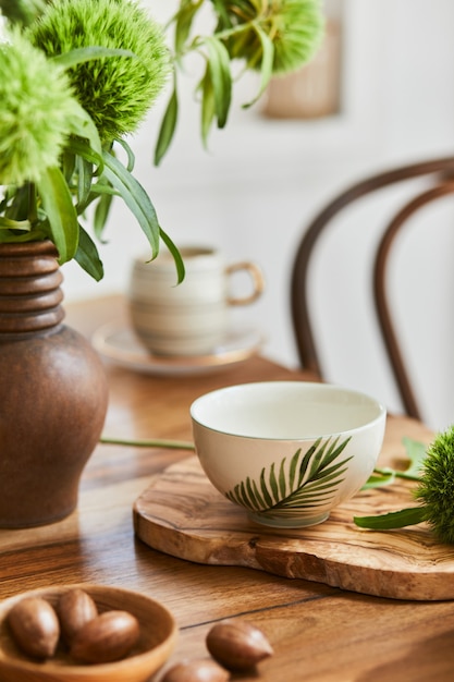 Composição elegante de design de interiores de sala de jantar elegante com mesa rústica, porcelana bonita, flores e acessórios de cozinha. Beleza nos detalhes. Modelo.