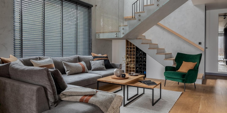 Foto composição elegante do design moderno da sala de estar com sofá cinza de canto poltrona verde mesa de centro e acessórios pessoais minimalistas escadas no interior da sala paredes de concreto modelo