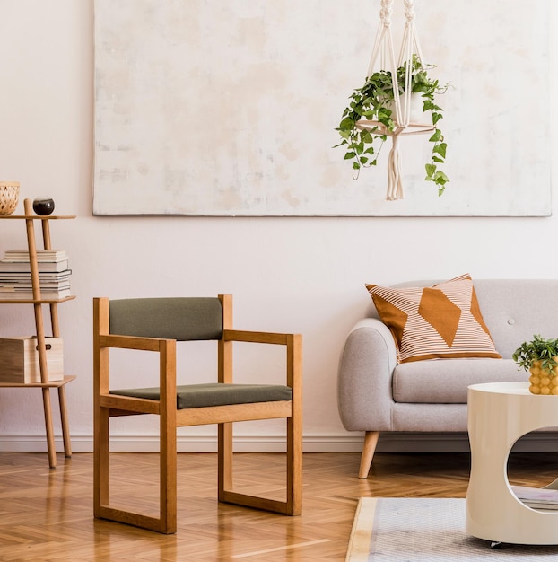 Composição elegante do interior da espaçosa sala de estar criativa com sofá cinza, cadeira, plantas, carpete, pinturas e acessórios. Paredes brancas e chão em parquet.