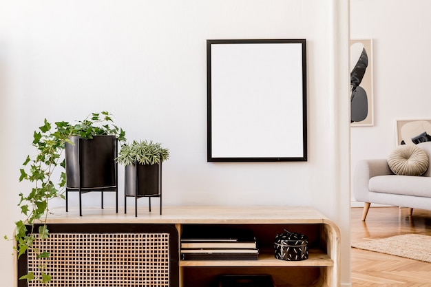 Composição elegante do interior da sala de estar com moldura, parede branca, plantas verdes em vasos elegantes na cômoda escandinava de madeira. Conceito minimalista. Copie o espaço.