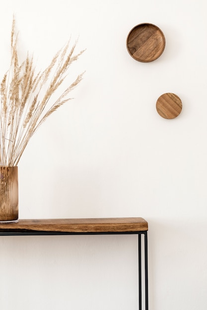 Composição elegante do interior da sala de estar com parede branca, plantas verdes em vasos de design moderno branco no console escandinavo de madeira. Conceito minimalista. Copie o espaço.