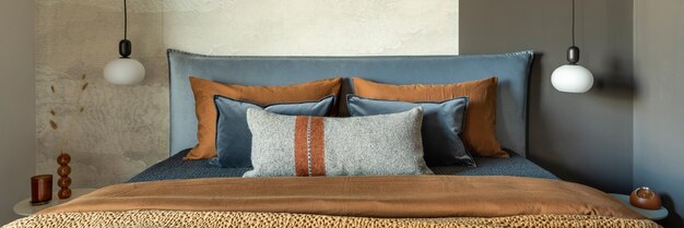 Composição elegante do interior do quarto moderno Lâmpada criativa de cama e acessórios pessoais elegantes Parede de concreto Lençóis marrons Conceito masculino minimalista Modelo