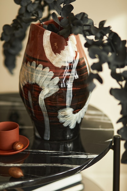 Composição elegante no interior chique com mesa de centro de mármore, flor de eucalipto em um vaso e xícara de café na decoração moderna. Detalhes.