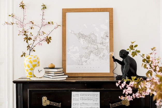 Composição elegante no interior da sala de estar com piano preto, mapa de pôster, flores secas, relógio branco, livro, lâmpada e acessórios pessoais elegantes em decoração moderna.