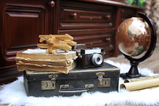 Composição em um globo vintage de piso de madeira com uma velha mala de couro com objetos para viagens